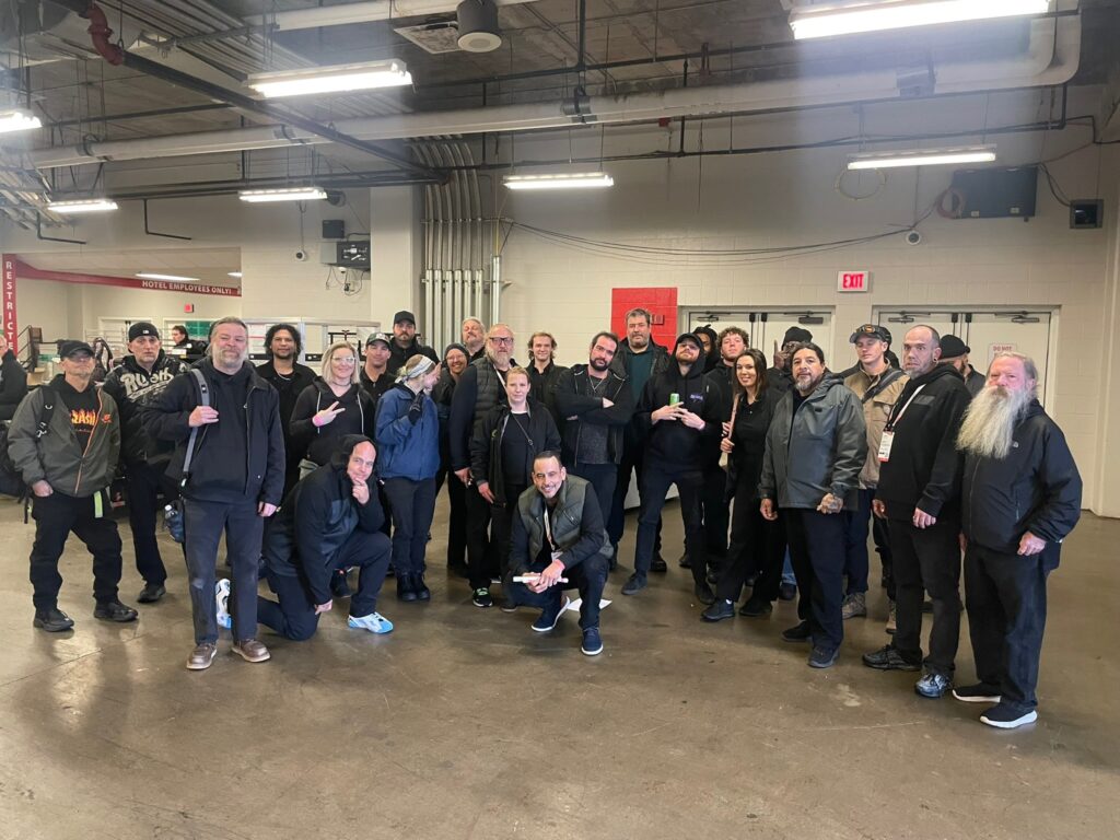 A professional technical crew representing the AV Labor Source Spotlight posing together in a venue's backstage preparation area.